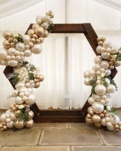 organic balloon garland with flowers on hexagon wood frame.